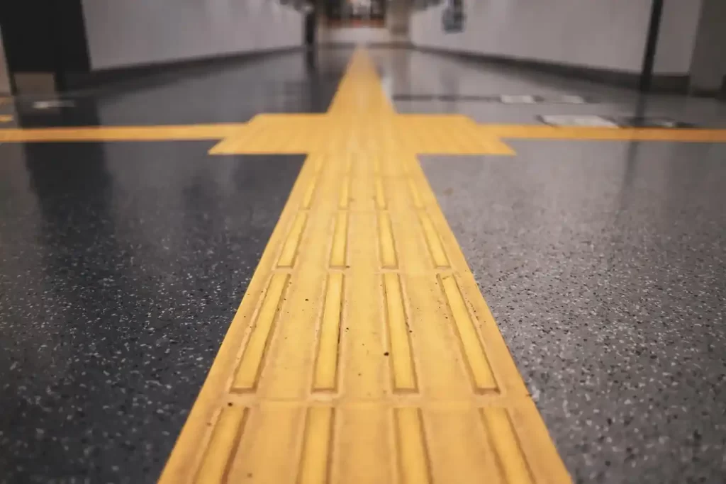 Piso tátil direcional em ambiente interno, instalado no chão para orientar a locomoção de pessoas com deficiência visual.