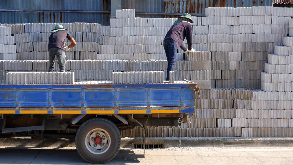 Trabalhadores descarregando blocos de concreto em caminhão para obra de construção civil